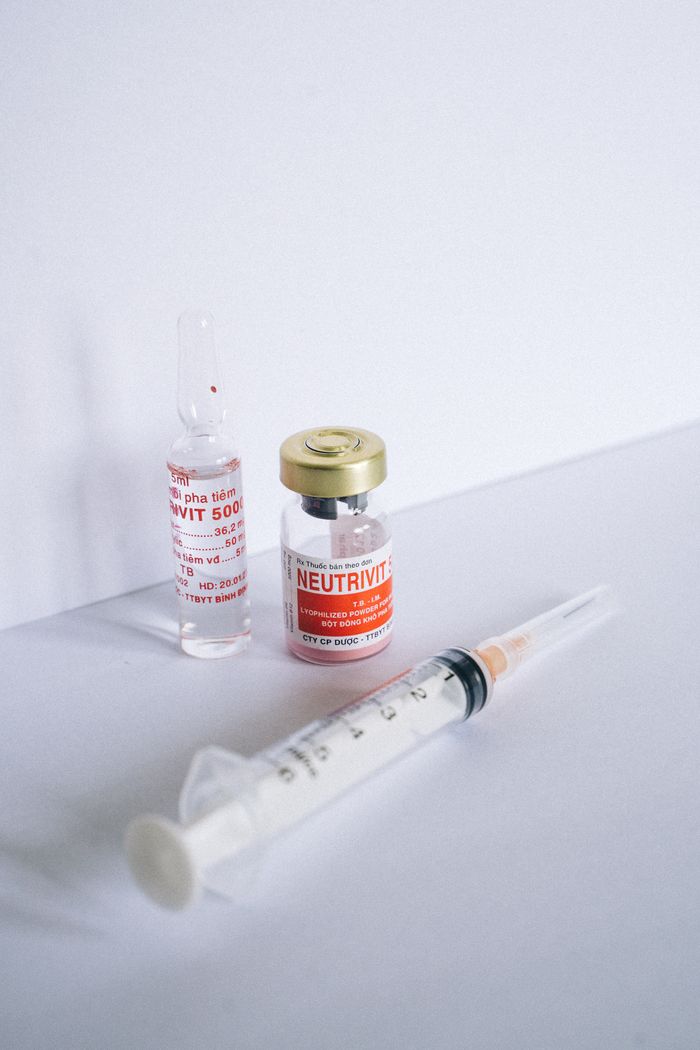 A close-up of a medical vial and syringe on a white background, reflecting healthcare themes.